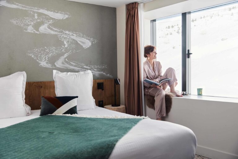 Voyageuse profitant d’un coin lecture avec vue montagne à l’Hôtel VoulezVous by Les Étincelles