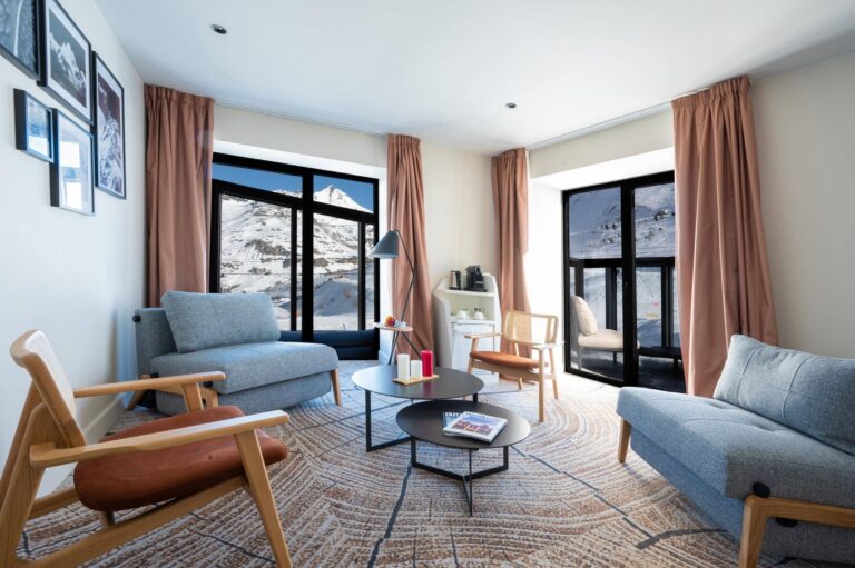 Salon lumineux d’une suite de l’Hôtel VoulezVous by Les Étincelles avec vue sur les sommets enneigés de Tignes