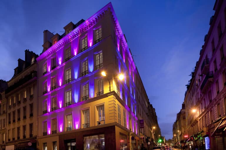 Façade illuminée en violet du Secret de Paris Hotel & Spa
