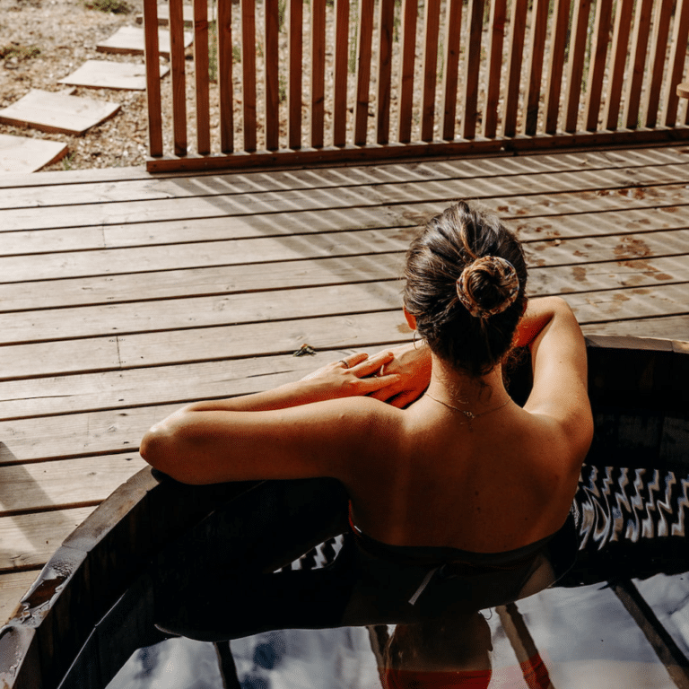 Espace détente extérieur en bois à La Maison du Val avec fauteuils et bain chaud