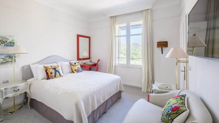 Chambre lumineuse avec fauteuil et balcon au COMO Le Beauvallon