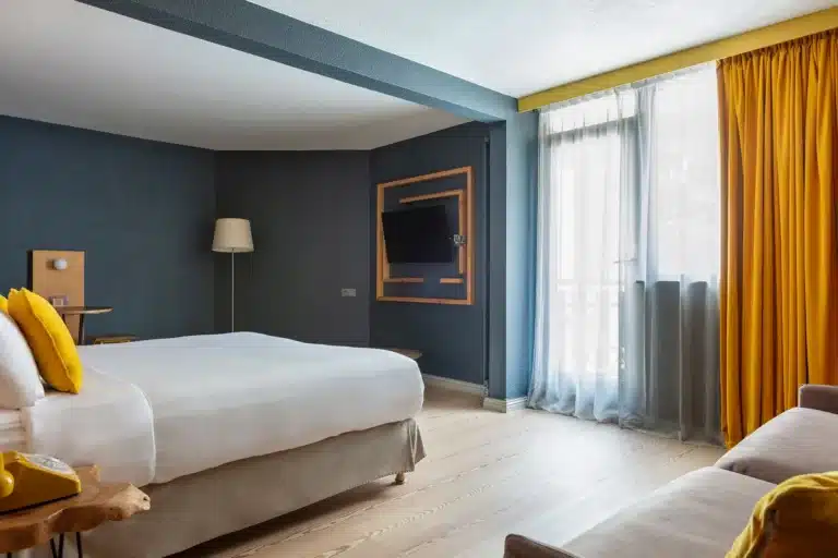 Suite Junior de l’Hôtel Les Aiglons à Chamonix avec grand lit et coin salon.